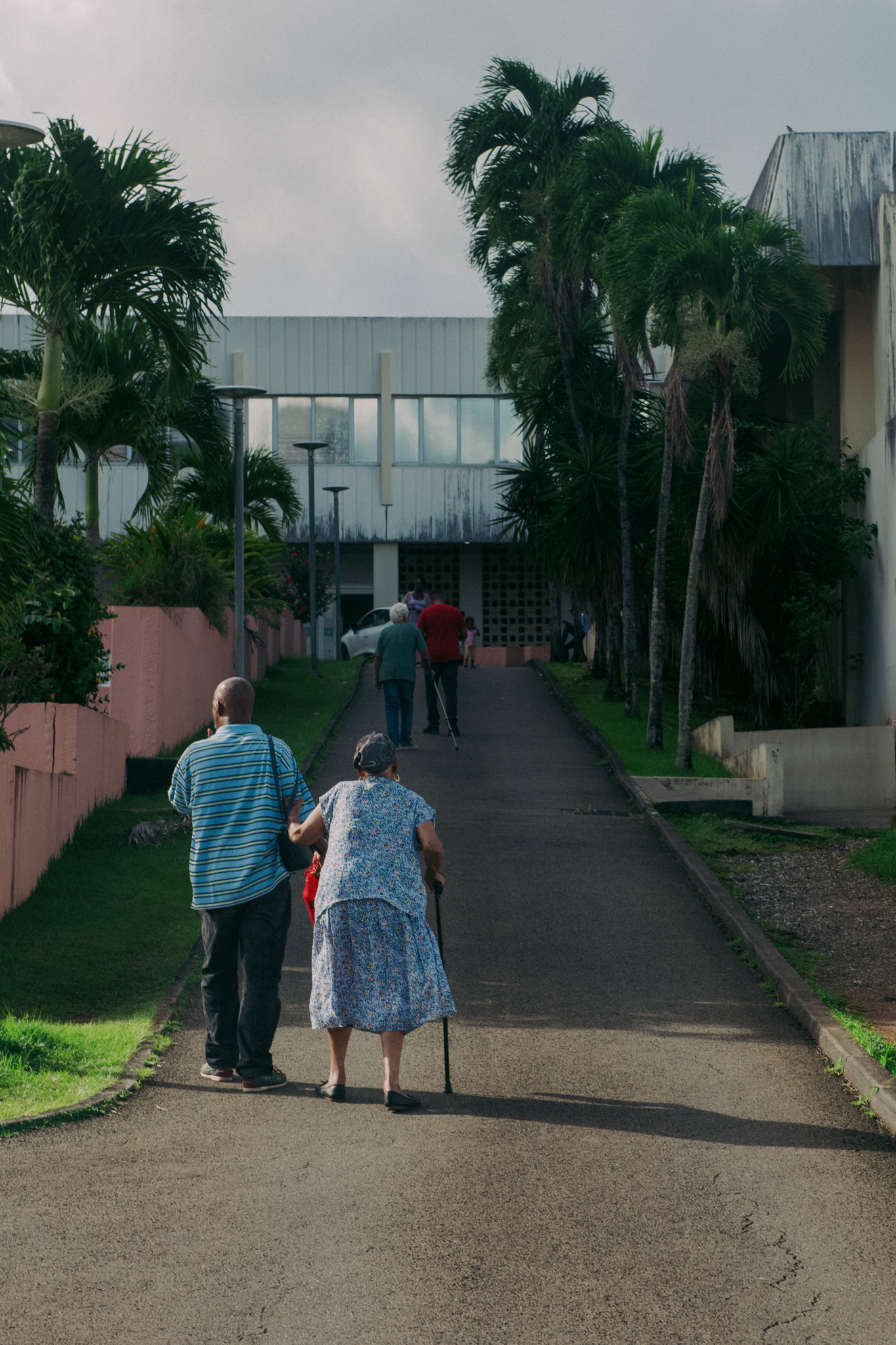 Un couple de dos se tenant par le bras qui marche vers un bâtiment